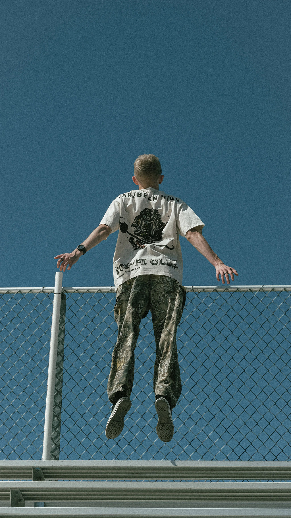 HAS/BEEN HIGH sci fi club oversized heavyweight tee beige back graphic on male model jumping on bleachers streetwear